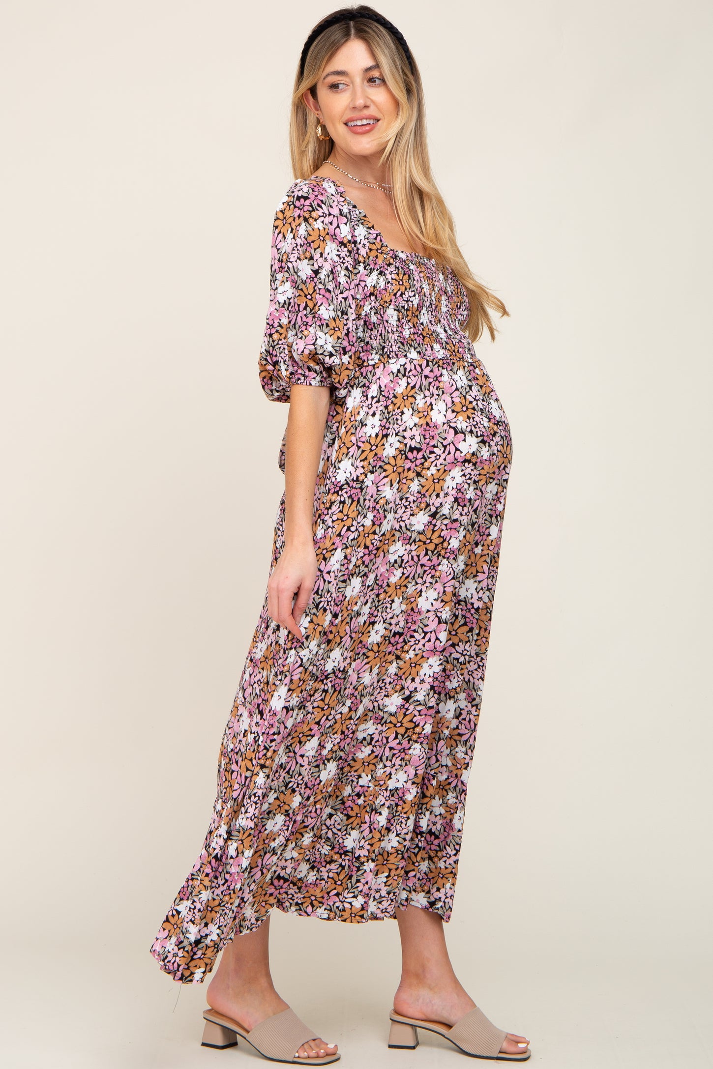 Pregnant woman wearing a floral smocked maternity maxi dress with puff sleeves and tan block heel sandals