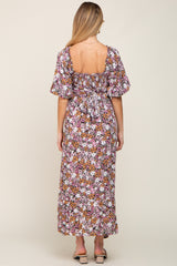 Back view of a woman wearing a pink and orange floral maxi dress with puff sleeves and a smocked tie back.