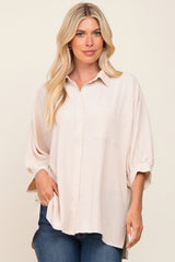 blonde woman wearing an oversized beige button-down shirt and blue jeans