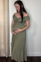 woman wearing an olive green off-the-shoulder maternity dress and holding her baby bump