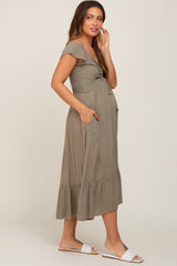 pregnant woman wearing olive green smocked maternity midi dress with ruffle sleeves and pockets