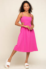 Woman wearing a hot pink midi dress with scalloped edges and side cutouts paired with white platform sandals