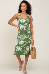 woman wearing a green floral knit midi dress and holding a straw bag