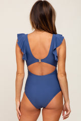 woman wearing a blue one-piece swimsuit with ruffle details and an open back design