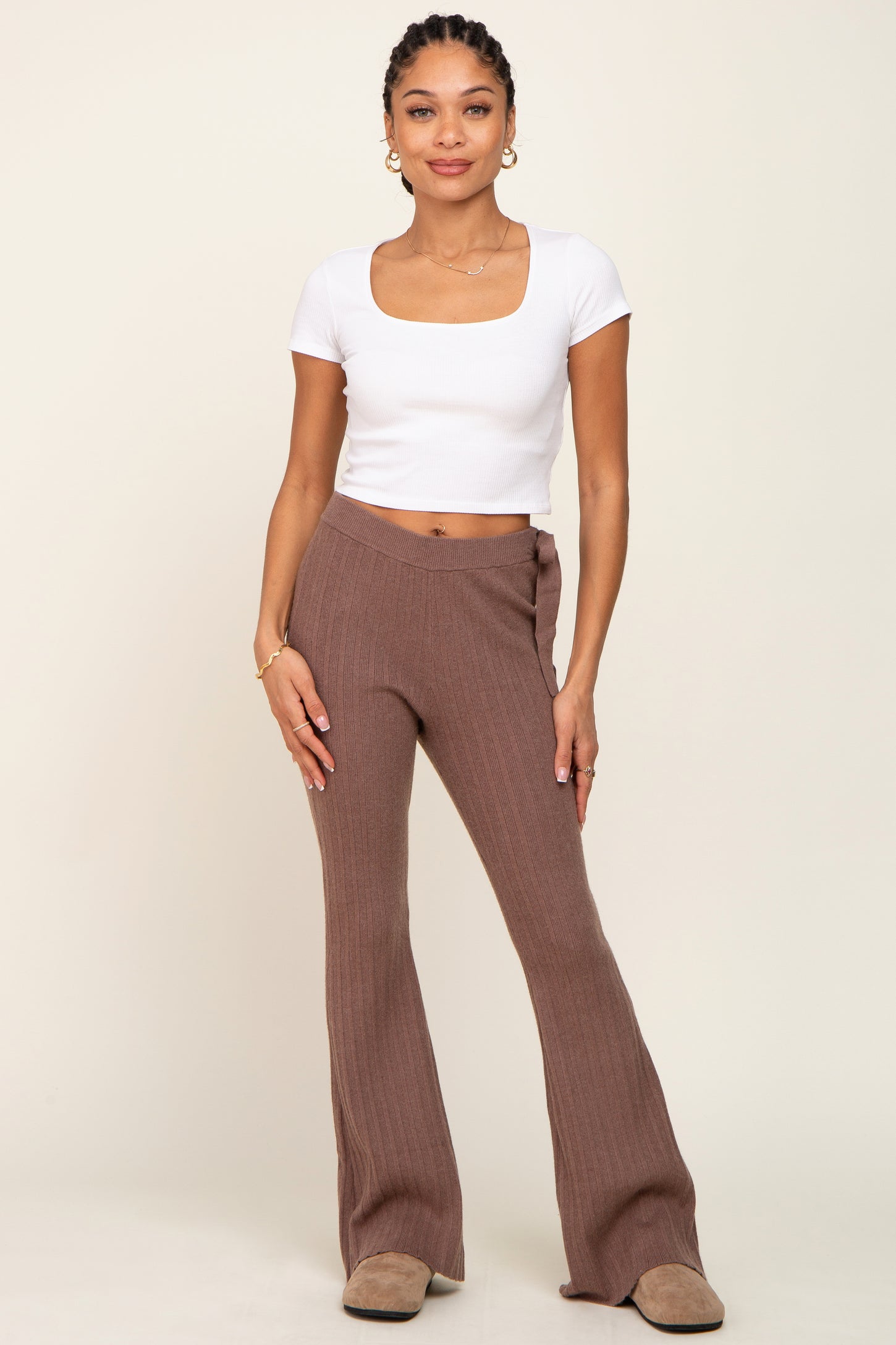 woman wearing a white short sleeve crop top and brown ribbed flared pants