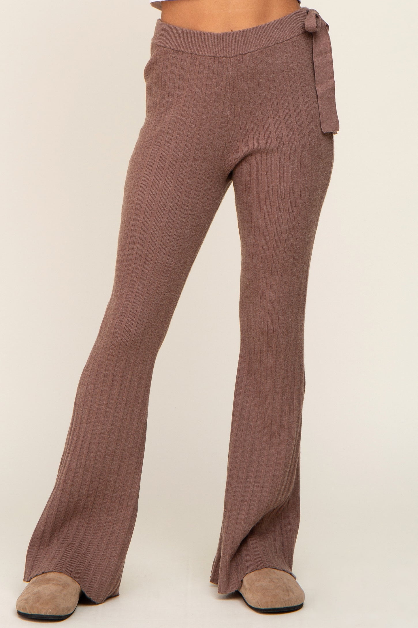 woman wearing mauve ribbed knit flared pants with a tie waist detail and ankle-length hems
