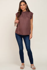 woman wearing a mauve flutter sleeve maternity top and dark wash skinny jeans with tan slide sandals