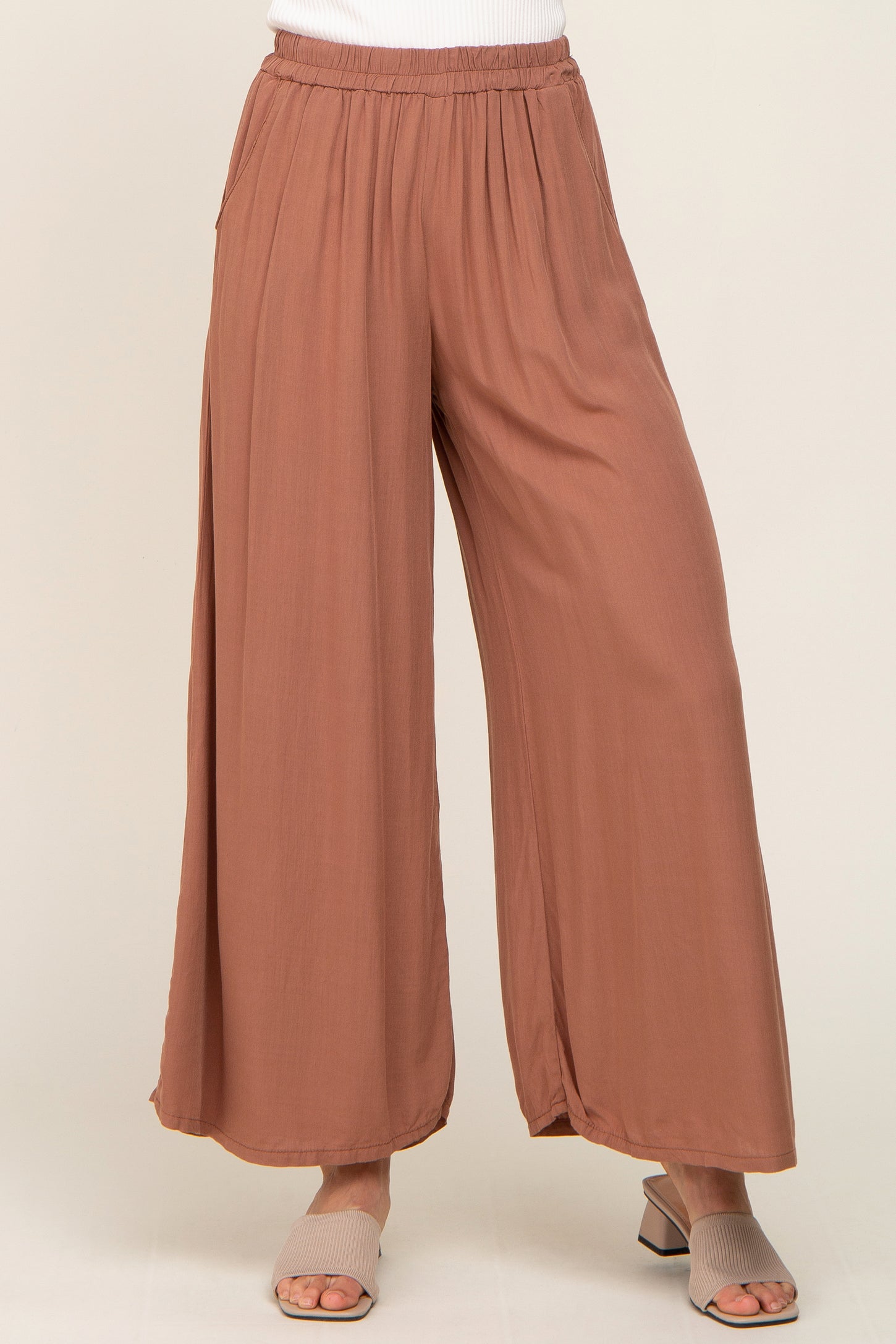 woman wearing mauve wide leg palazzo pants with elastic waistband and tan block heel sandals