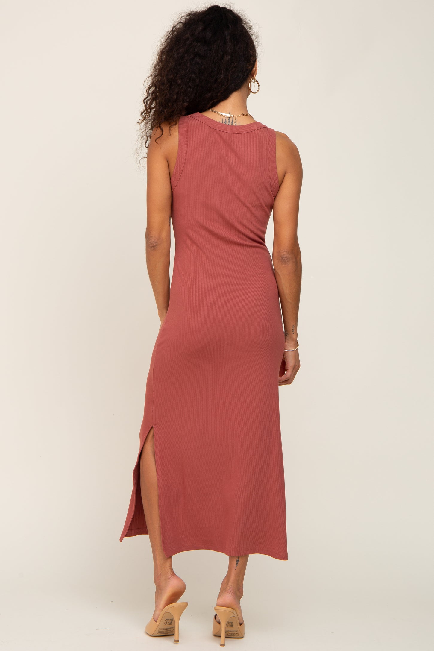 woman wearing a dusty rose sleeveless maxi dress with a side slit and back view, paired with beige heeled sandals