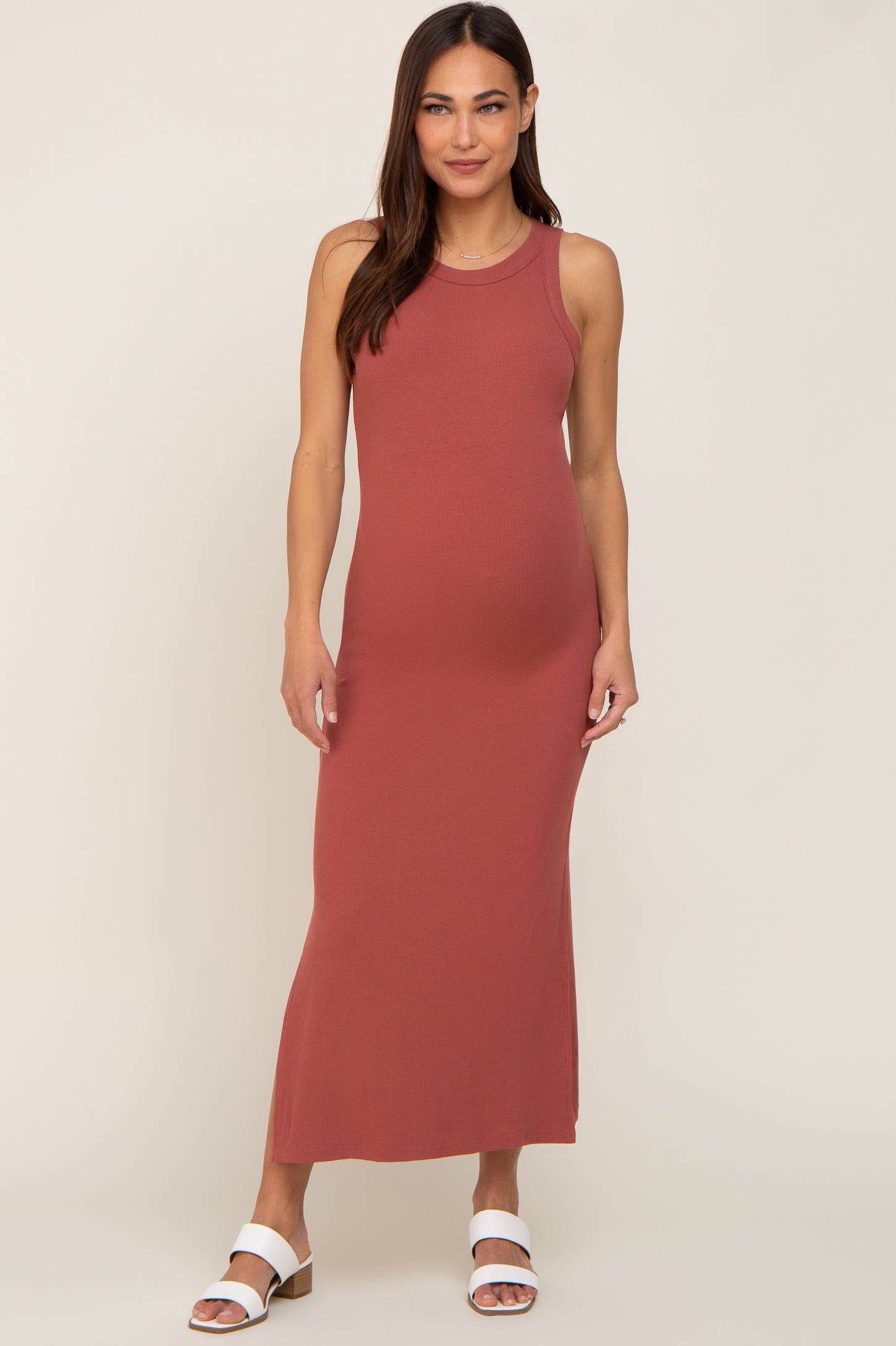 woman wearing a rust colored ribbed maternity maxi dress and showcasing her baby bump