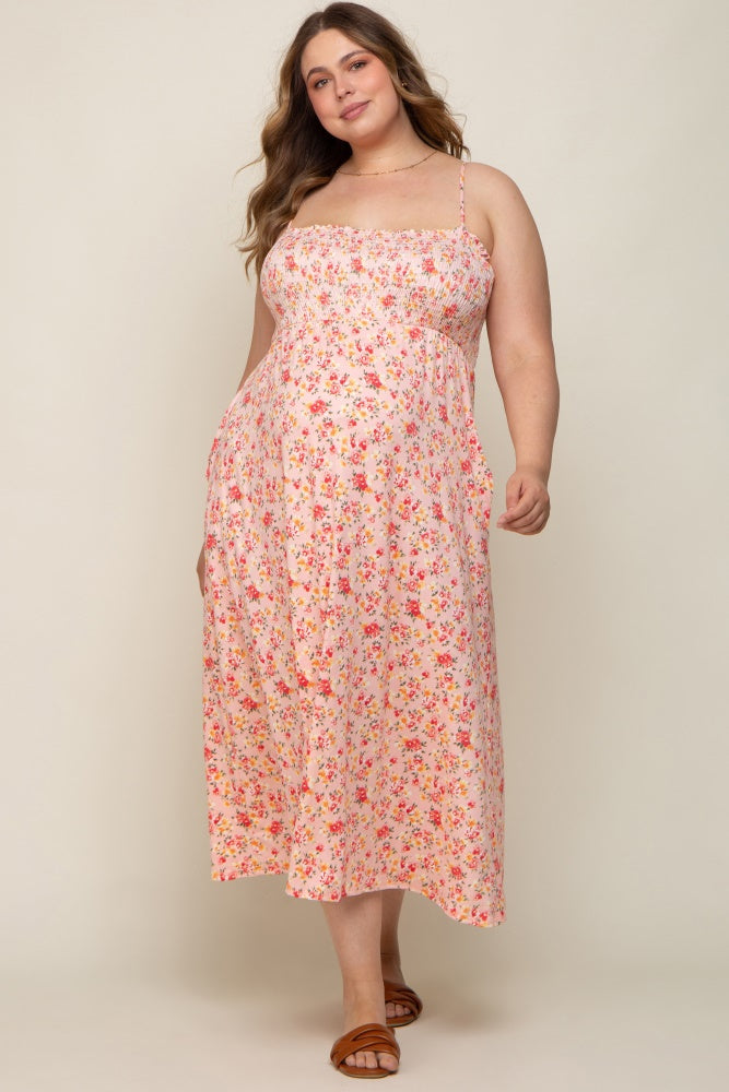 Pregnant woman wearing a pink floral smocked maternity midi dress with spaghetti straps