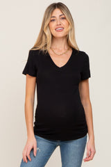 woman wearing a black v-neck maternity top and fitted jeans, showing her baby bump