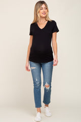 woman wearing a black v-neck maternity t-shirt and distressed blue jeans, showing her baby bump