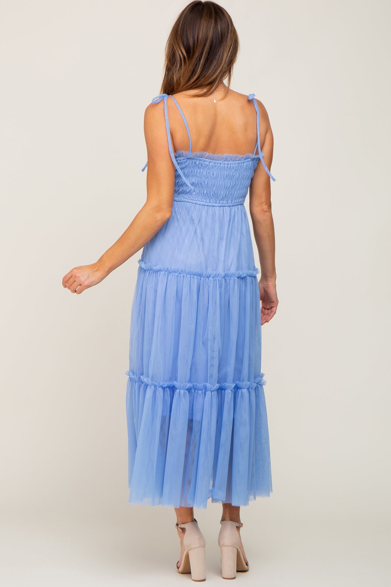woman wearing a light blue tiered tulle maxi dress with adjustable straps and a smocked bodice
