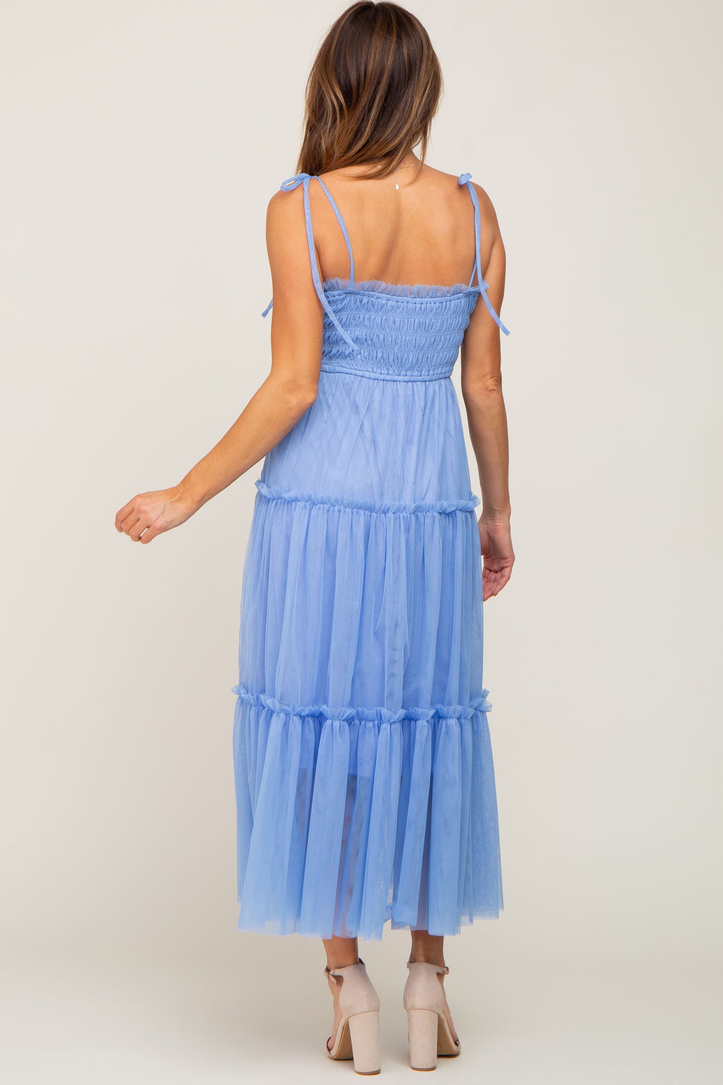 woman wearing a light blue tiered tulle maxi dress with adjustable straps and a smocked bodice