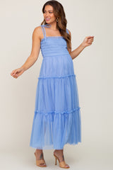 woman wearing a light blue tiered maternity dress with smocked bodice and spaghetti straps, showing her baby bump