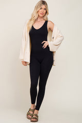 woman wearing a black bodysuit with a cream cardigan and brown sandals