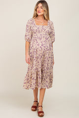 woman wearing a purple floral smocked maternity midi dress with puff sleeves and brown sandals