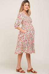 Pregnant woman wearing a floral smocked maternity midi dress with pockets and brown sandals
