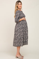 pregnant woman wearing a black floral smocked maternity midi dress with three-quarter sleeves
