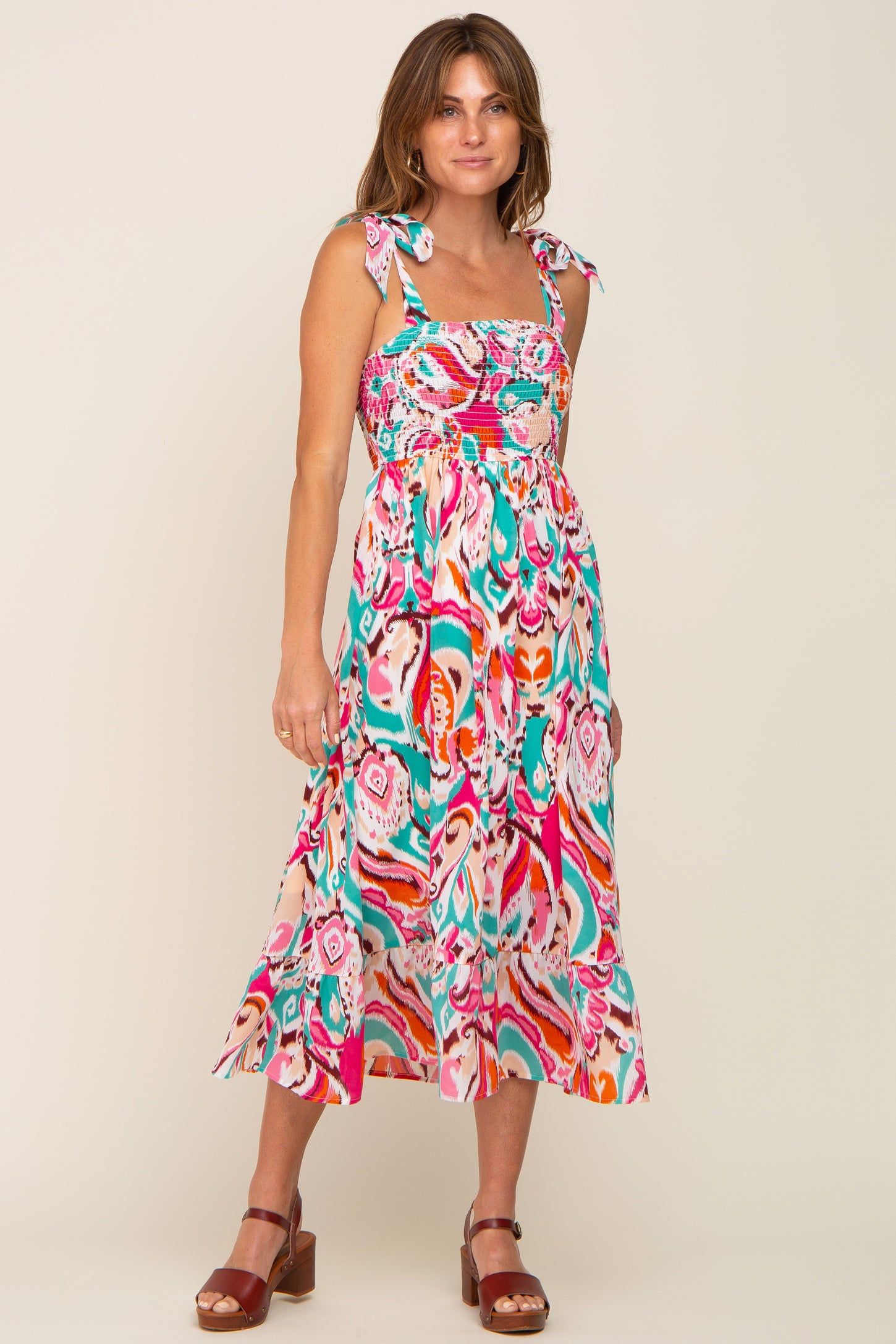 woman wearing a colorful paisley print midi dress with tie straps and smocked bodice