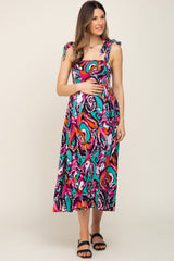 woman wearing a colorful patterned maternity maxi dress with adjustable tie straps and holding her baby bump