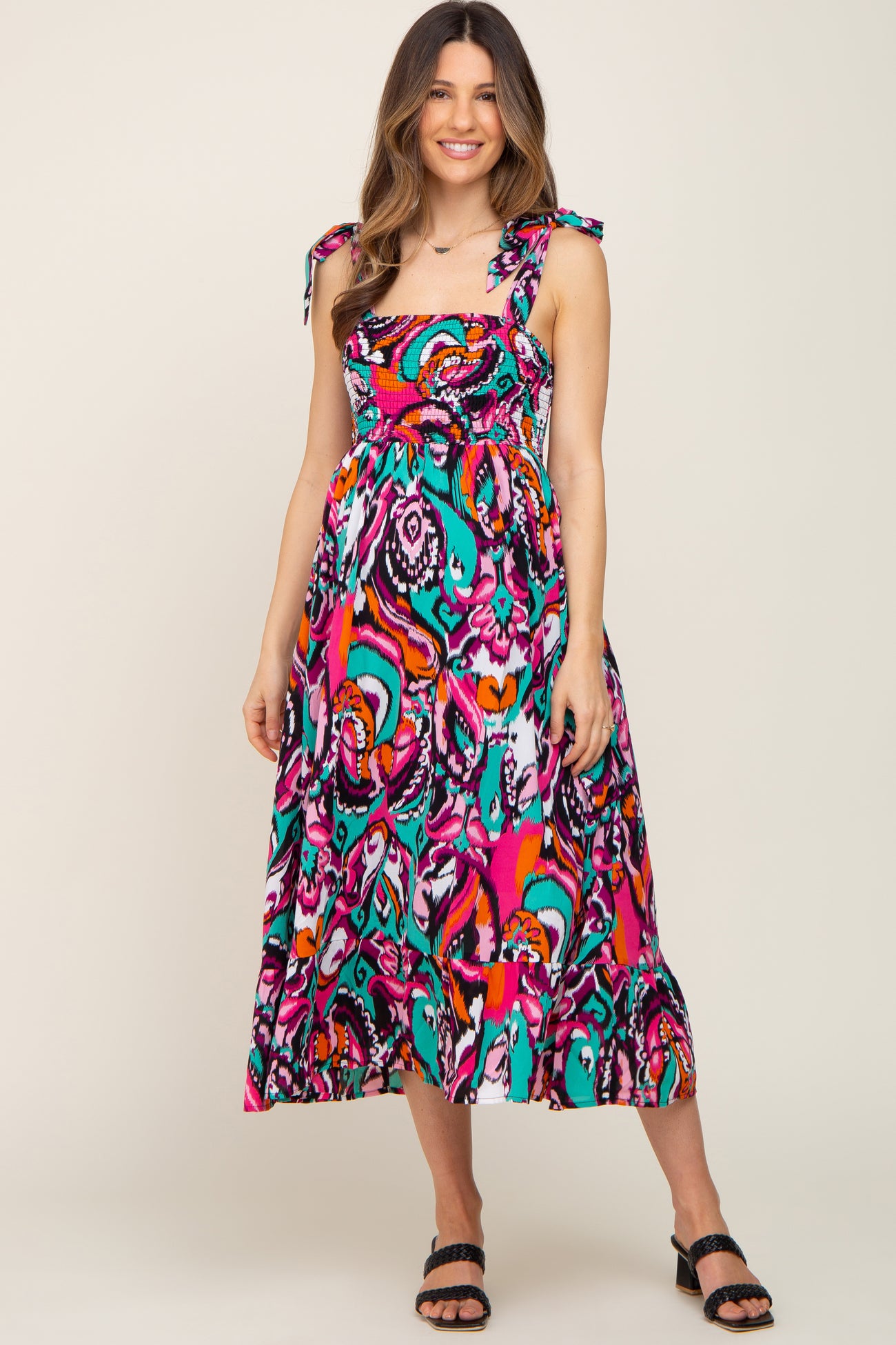 woman wearing a colorful patterned maternity dress with tie straps and a flowing skirt, baby bump visible