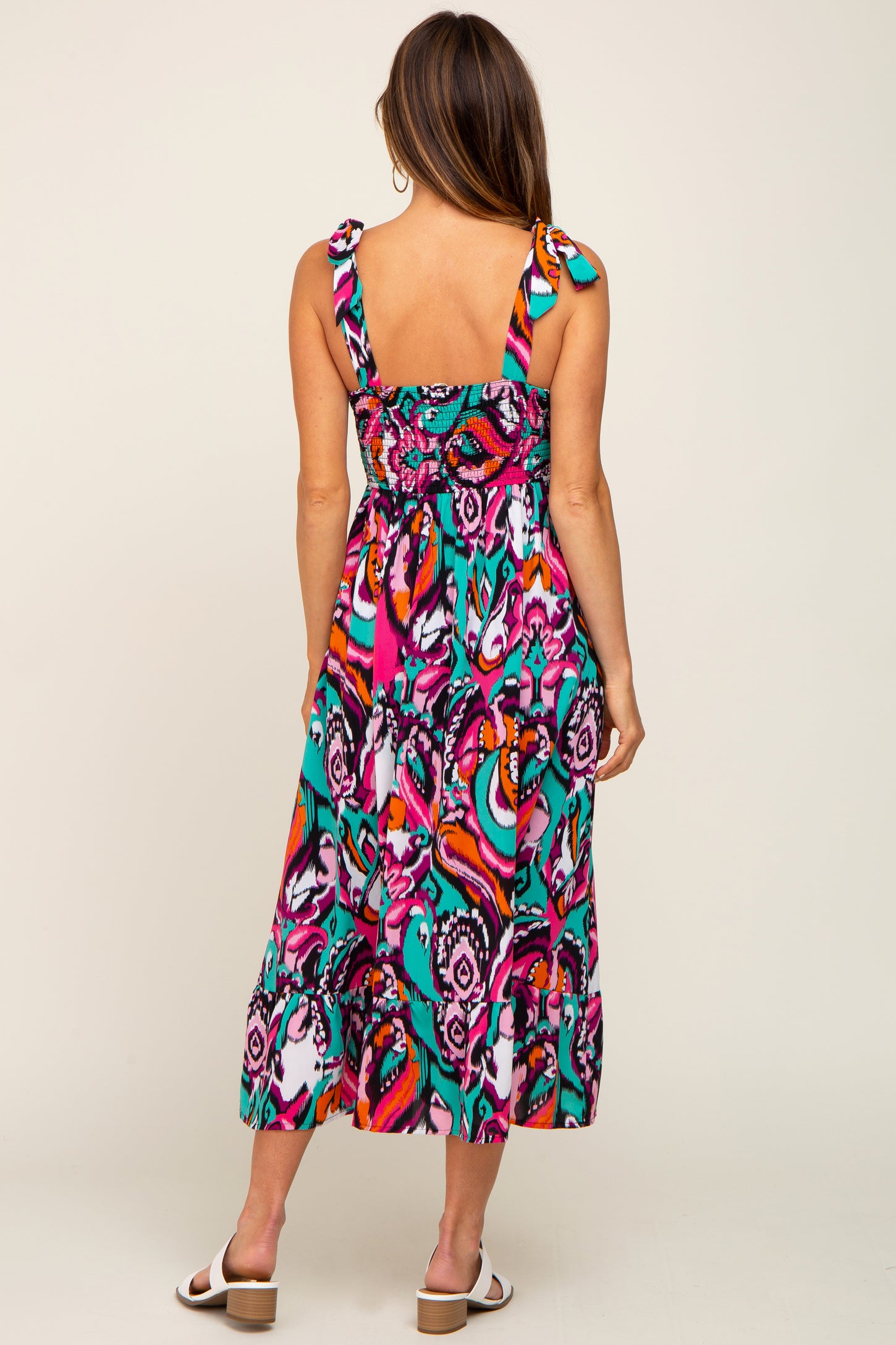 woman wearing a colorful floral midi dress with tie straps and a smocked back