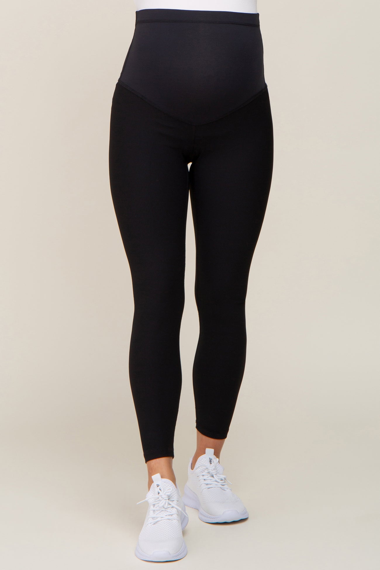 person wearing black ribbed maternity leggings with over-the-belly support and white sneakers