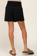 woman wearing black smocked waist shorts with scalloped hem