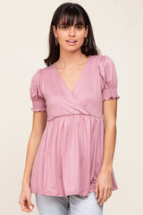 woman wearing a pink v-neck top with puff sleeves and gathered details, styled with light blue jeans
