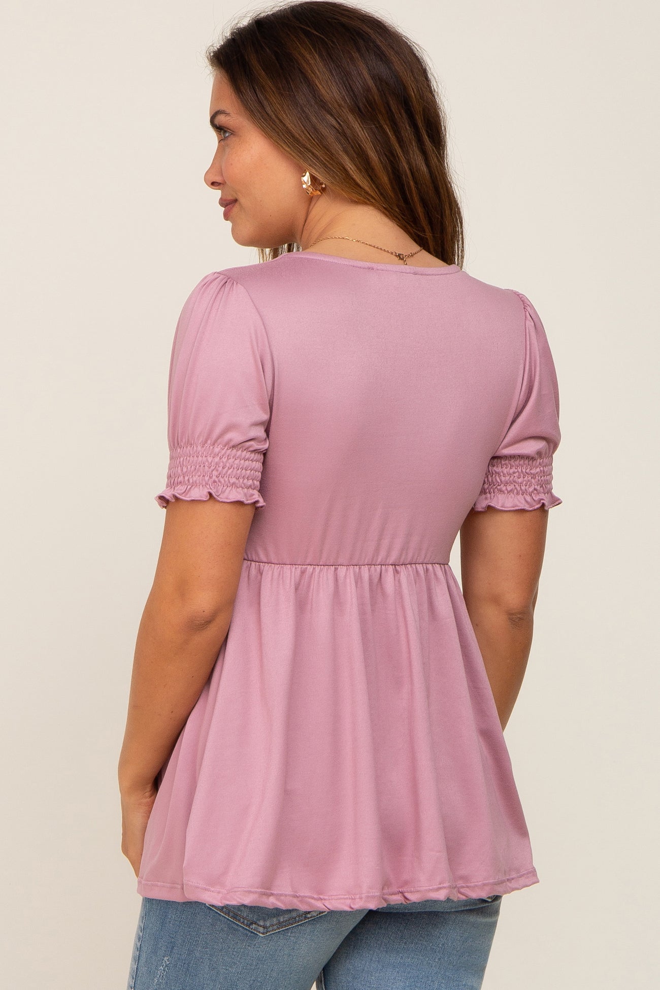 woman wearing a lilac maternity top with smocked short sleeves and a flowy hem