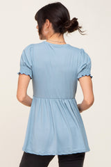 woman wearing a light blue puff sleeve top with a gathered waist and back view