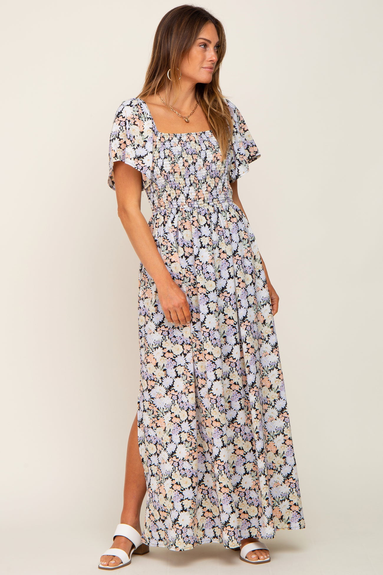 woman wearing a floral smocked maxi dress with flutter sleeves and side slit