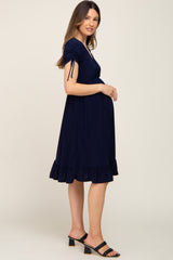 woman wearing a navy blue maternity dress with short sleeves and ruffle hem, showing her baby bump