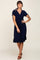 woman wearing a navy blue short sleeve wrap dress with tie details and a ruffled hem