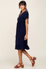 woman wearing a navy blue short sleeve dress with ruffle hem and a patterned scarf tied around her neck