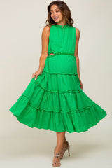 woman wearing a bright green maternity dress with tiered ruffles and a fitted waist, styled for a flowy look