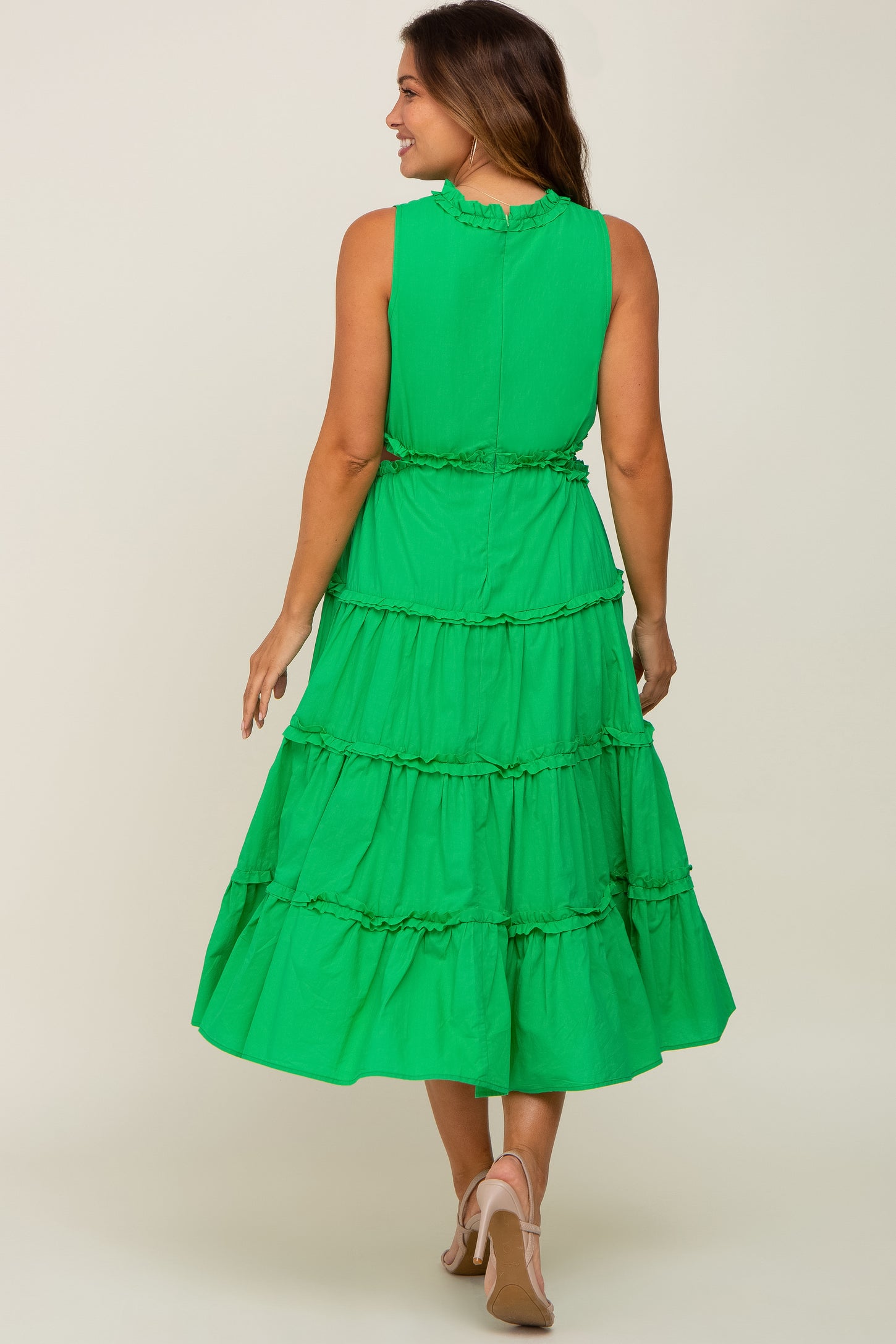 Woman wearing a green sleeveless tiered midi dress with ruffle trim and tan high heels