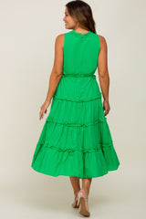 Woman wearing a green sleeveless tiered midi dress with ruffle trim and tan high heels