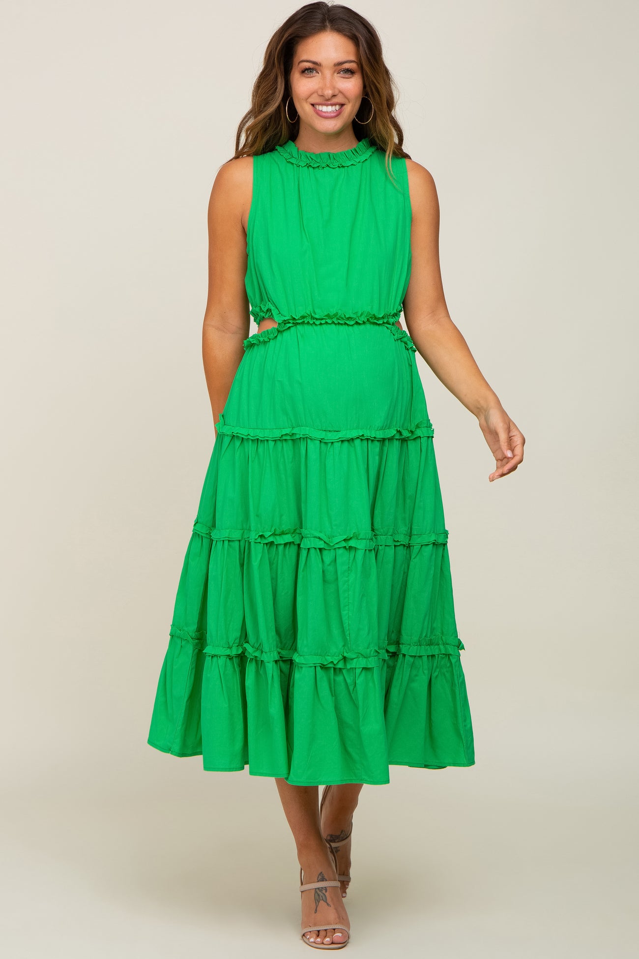 woman wearing a bright green maternity dress with a tiered design and ruffled details, showcasing her baby bump