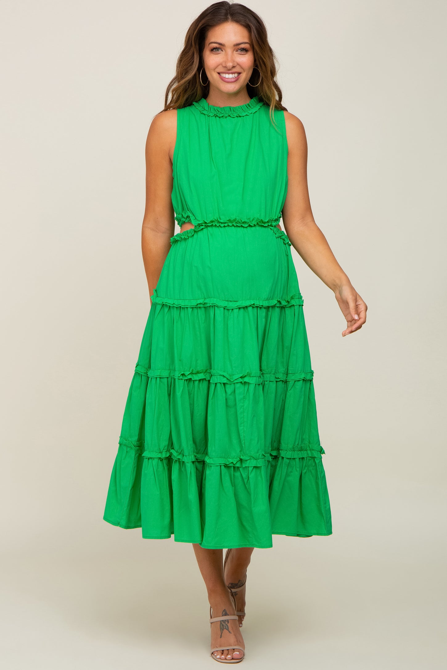 woman wearing a bright green maternity dress with a tiered design and ruffled details, showcasing her baby bump