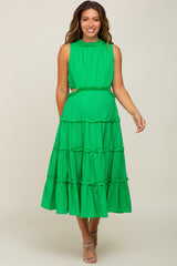 woman wearing a bright green maternity dress with a tiered design and ruffled details, showcasing her baby bump