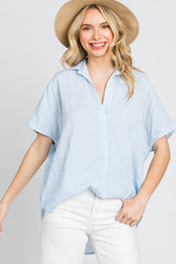 woman wearing a blue and white striped short sleeve button down shirt and straw hat