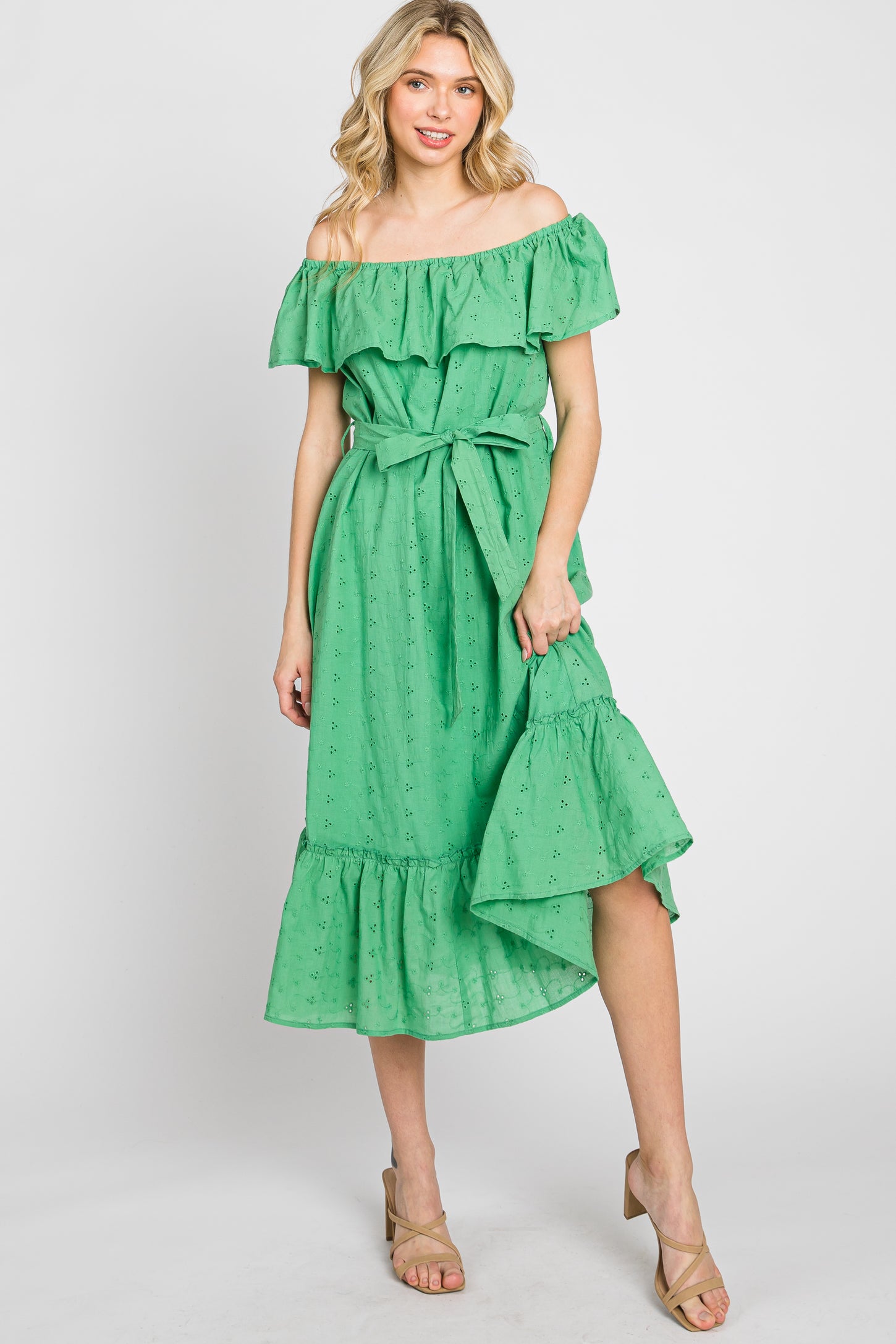 woman wearing a green off-the-shoulder eyelet midi dress with a ruffled hem and waist tie