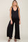 pregnant woman wearing a black sleeveless maternity jumpsuit with wide legs and black sandals