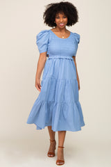 woman wearing a light blue smocked midi dress with puff sleeves and tiered skirt
