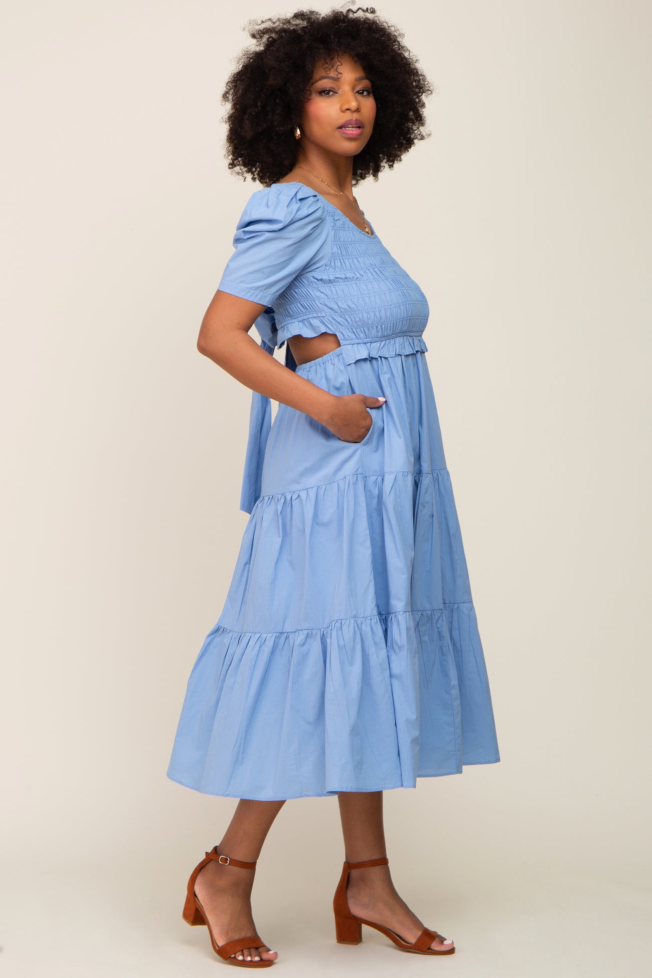 woman with afro hair wearing a light blue smocked midi dress with puff sleeves and side cutouts