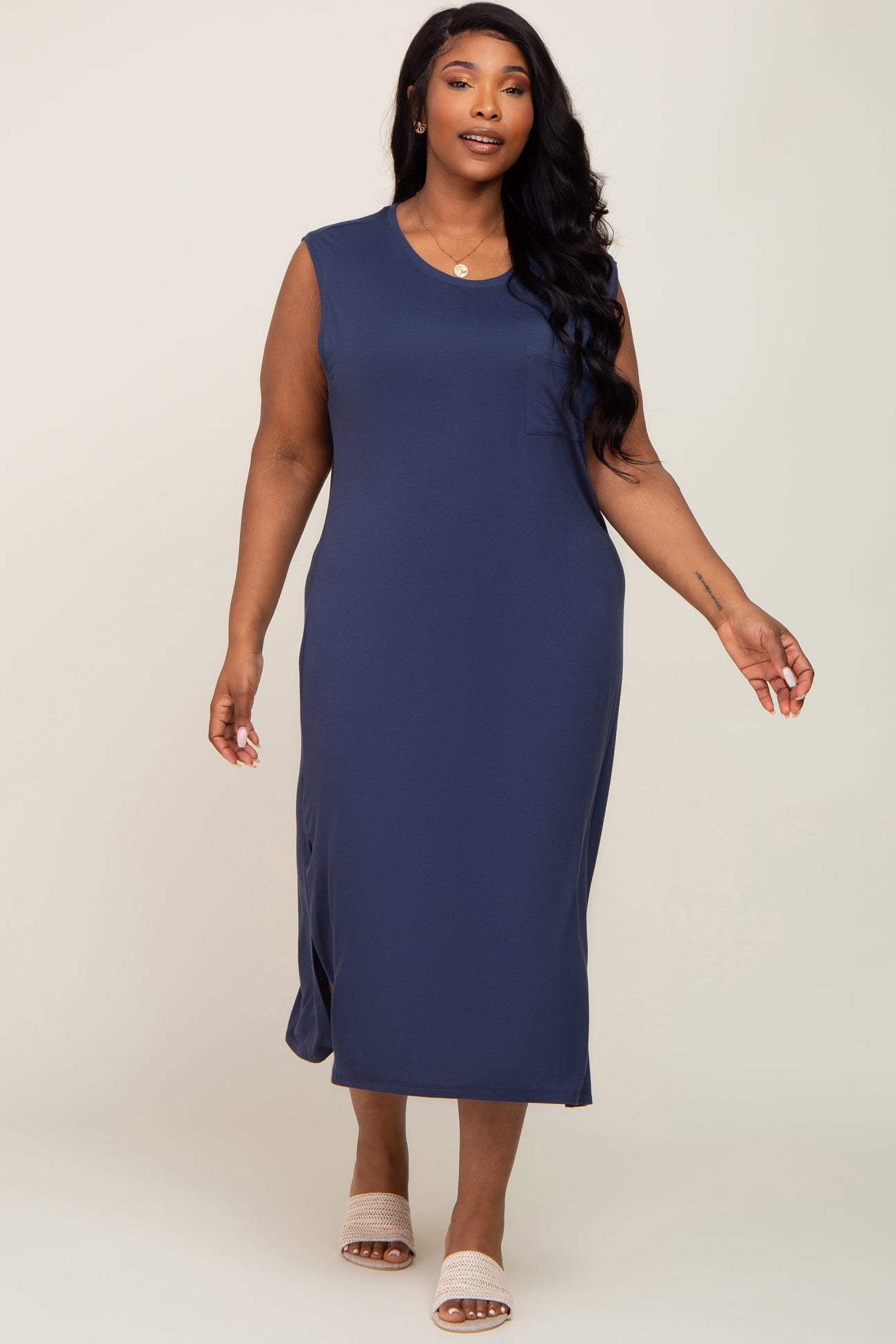 woman wearing a navy sleeveless midi dress with a chest pocket and side slits