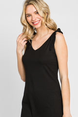 smiling blonde woman wearing a black ribbed v-neck dress with tie-shoulder straps